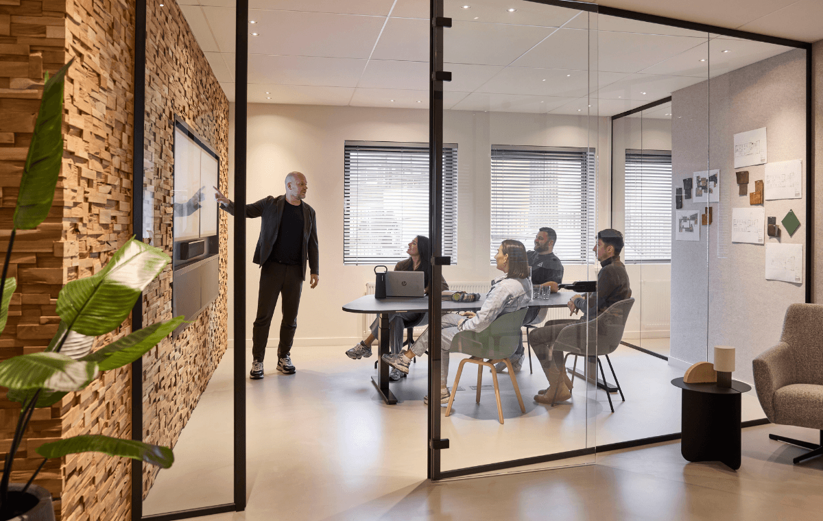 Medewerker presenteert een ontwerp aan collega’s in een glazen vergaderruimte