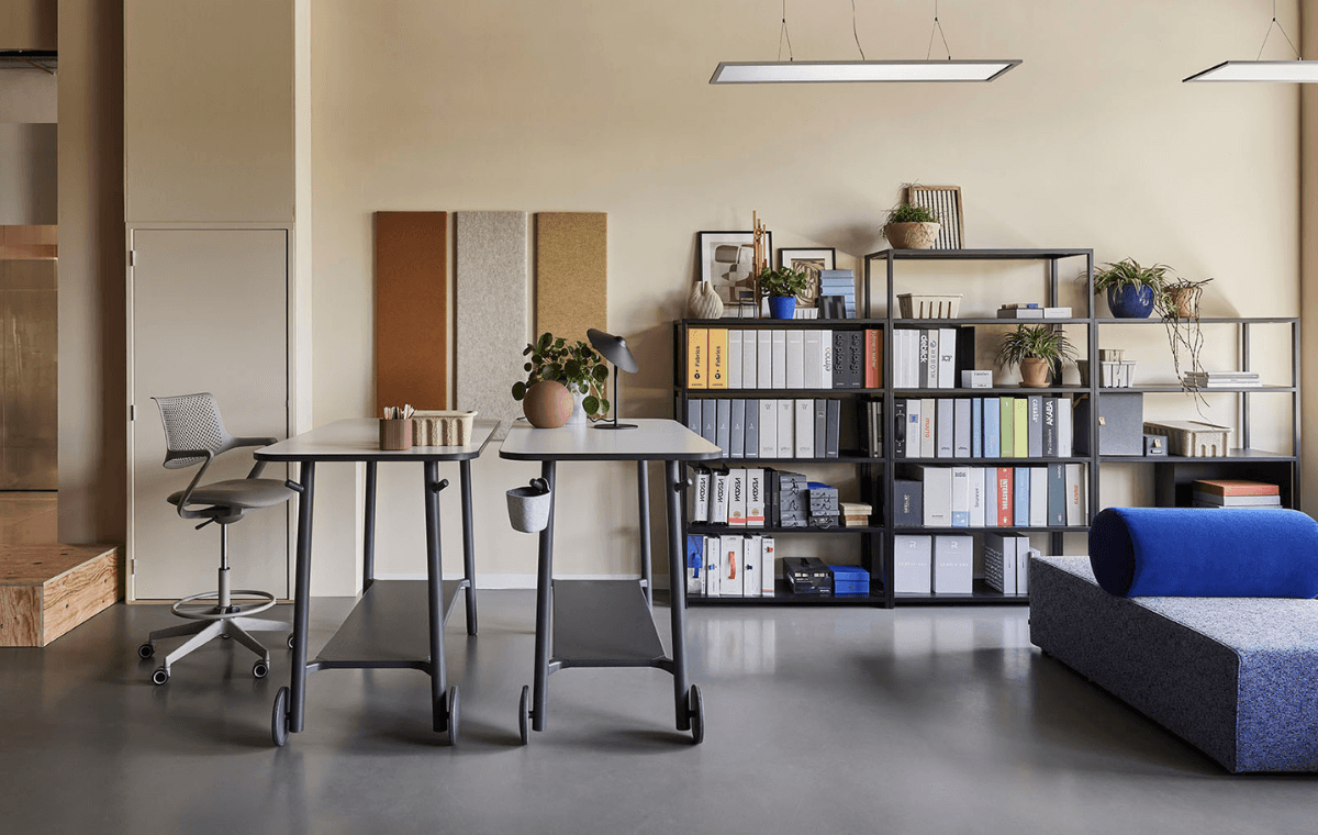 Open werkruimte met hoge bureaus, opbergrekken, planten en een loungeplek