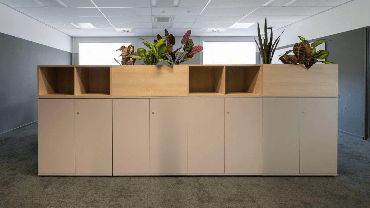 Vrijstaande houten opbergkast met open vakken en planten als ruimteverdeler
