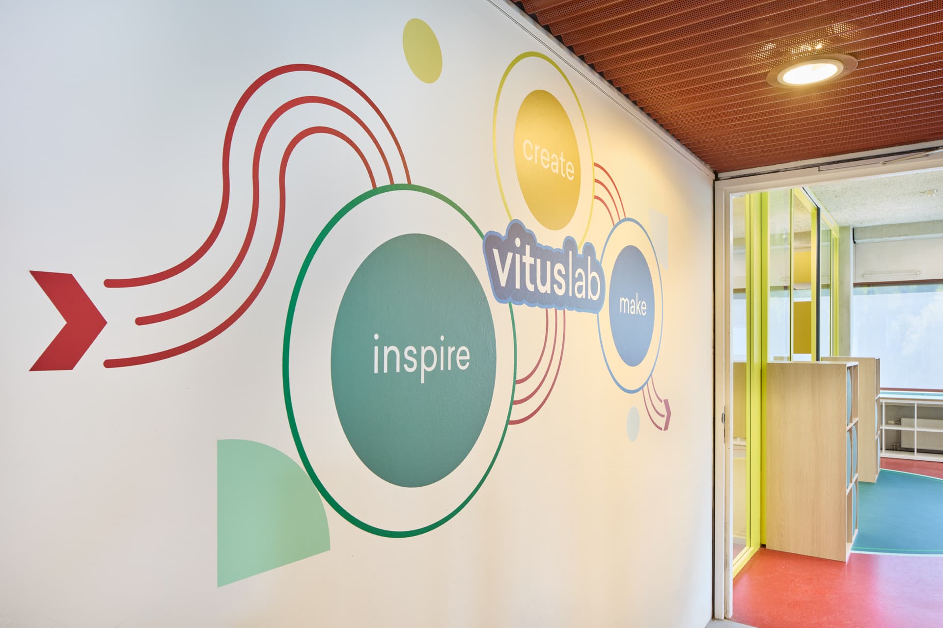 Wandillustratie met de woorden inspire, create en make bij de ingang van het Vituslab