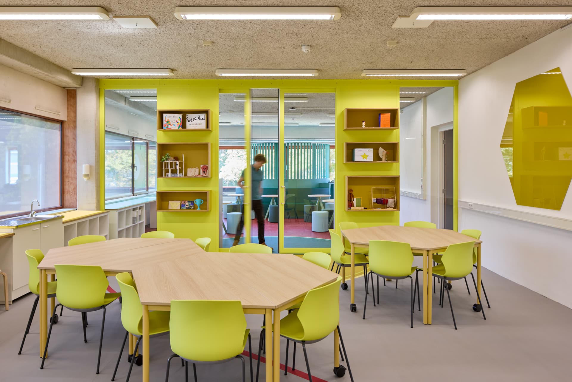Flexibel ingericht leslokaal met houten groepstafels en limegroene stoelen