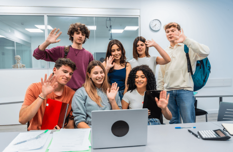 een gemixte groep van 7 leerlingen video bellen doormiddel van een laptop in een klaslokaal
