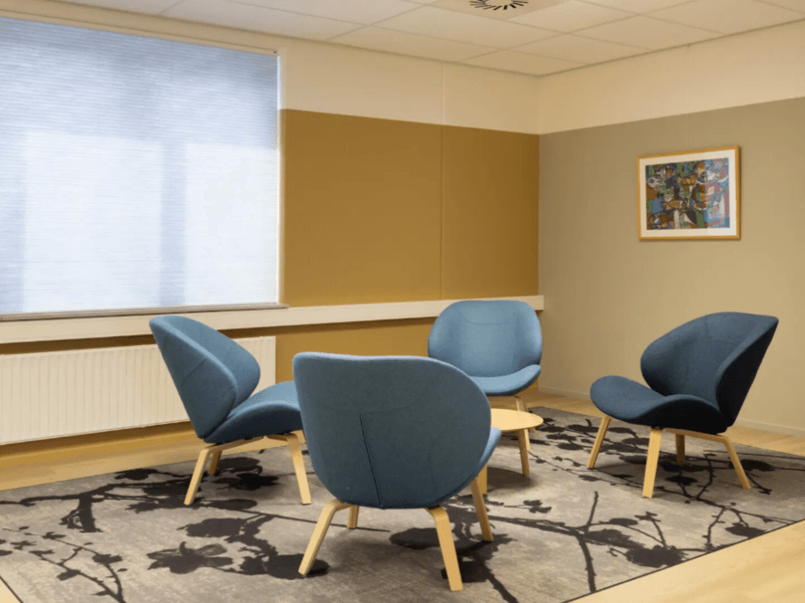 Informele overlegplek met vier blauwe fauteuils rond een kleine tafel