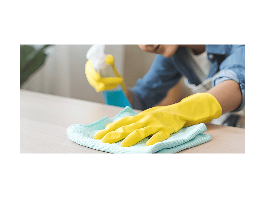 Medewerker reinigt een tafel met een microvezeldoek en schoonmaakspray.