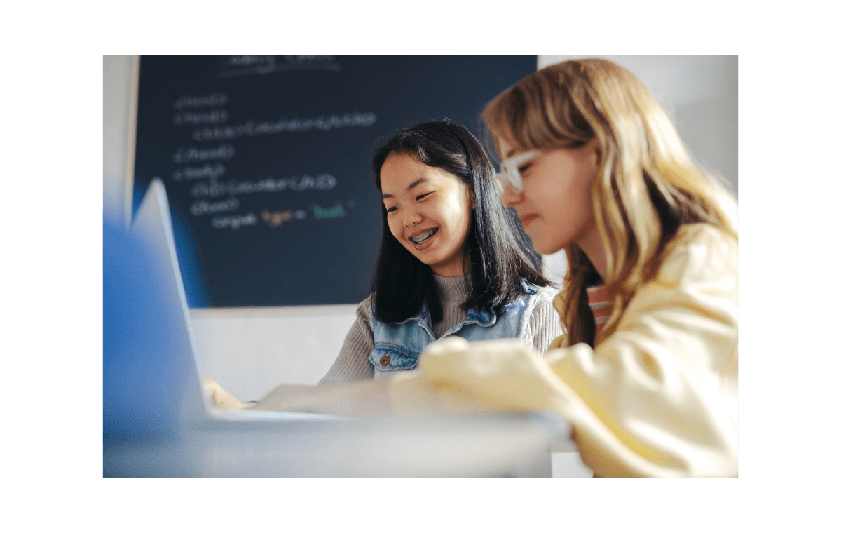 Twee leerlingen werken samen op een laptop in een lokaal.