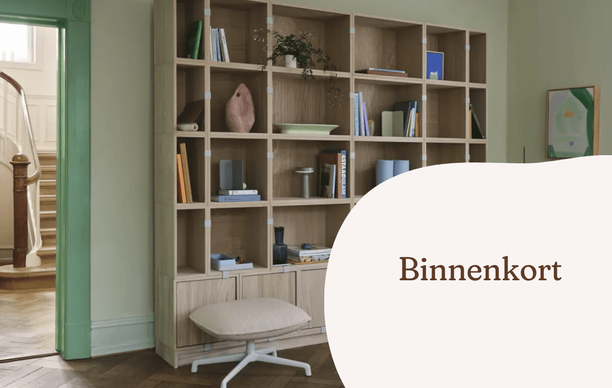 Houten vakkenkast met boeken, decoratie en een verrijdbare kruk in een kantoorruimte.