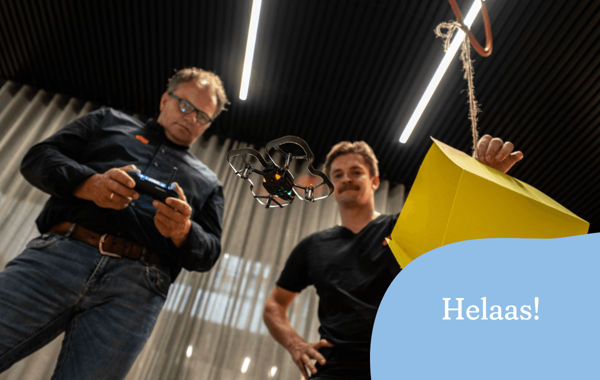 Twee docenten laten een drone door een parcours vliegen tijdens een technieksessie