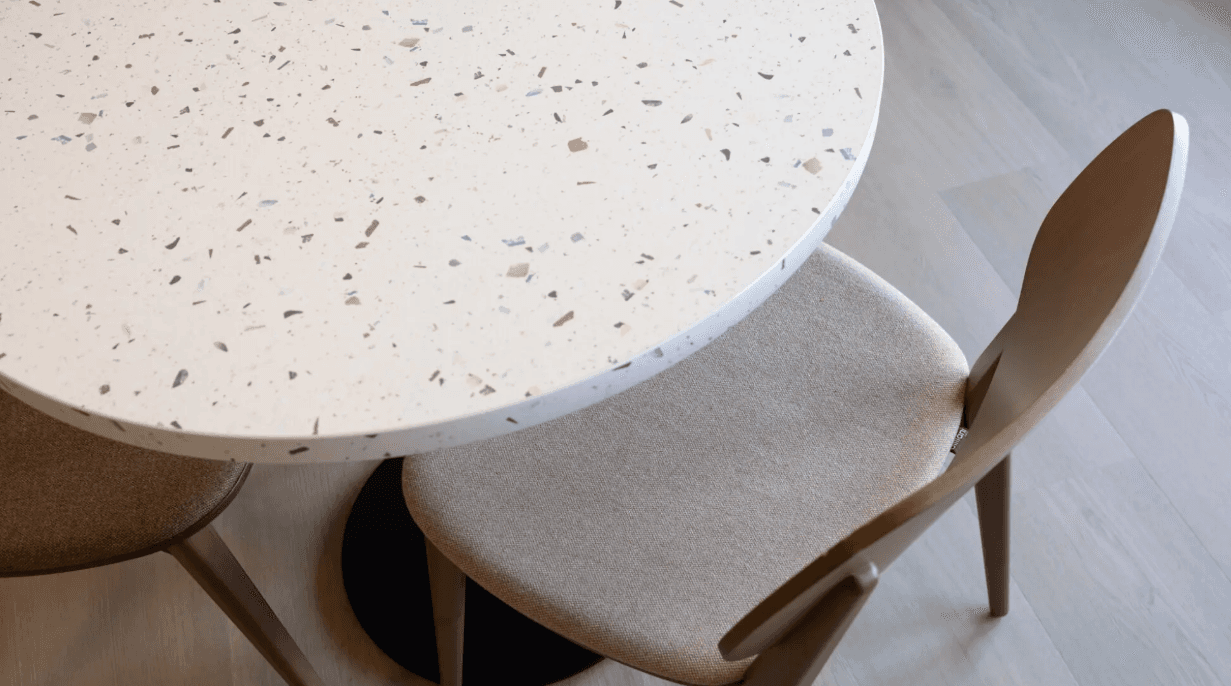 Ronde tafel met terrazzo-look tafelblad en houten stoelen met gestoffeerde zitting