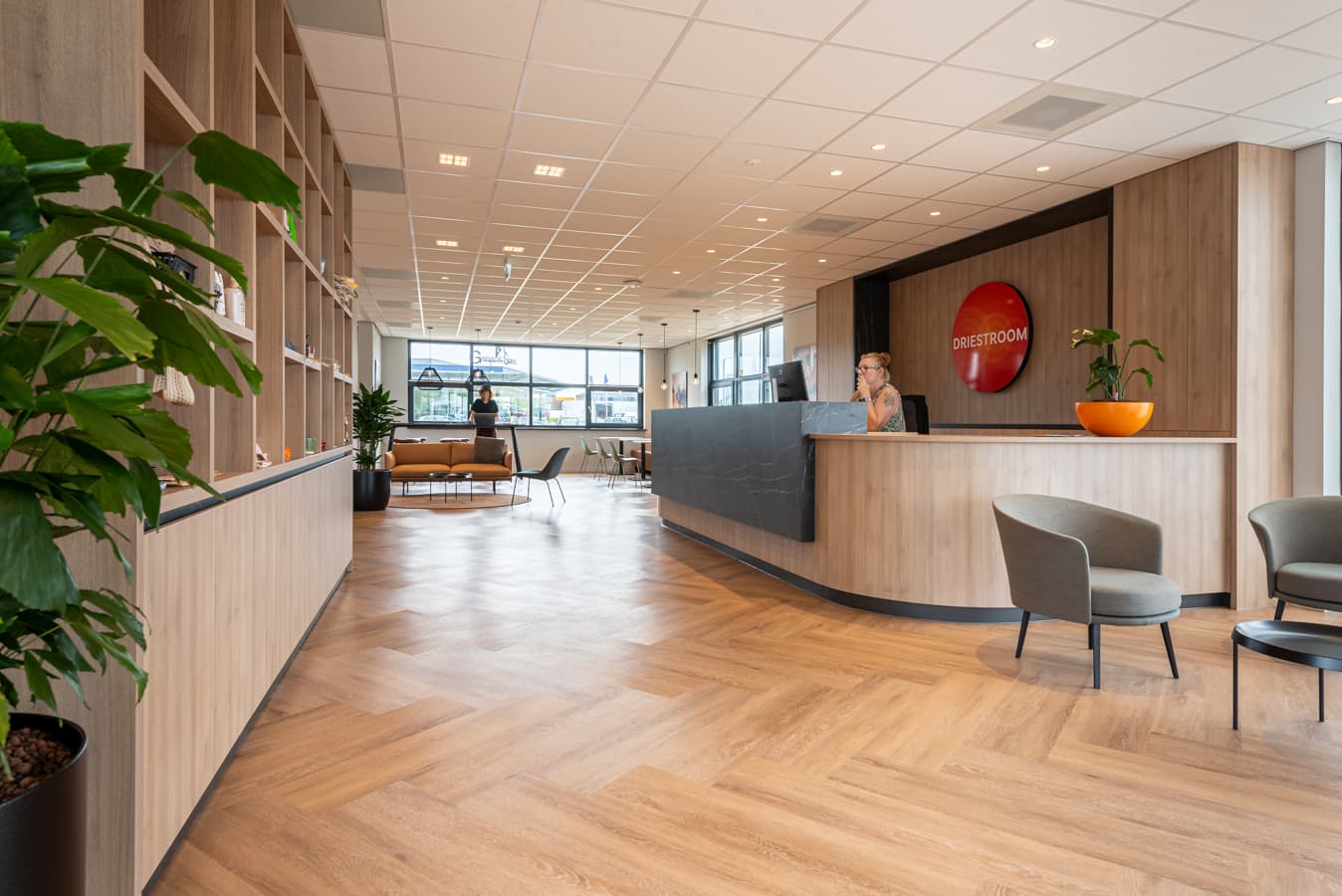 Ontvangstruimte met gebogen receptiebalie, houten kastenwand en zitplaatsen