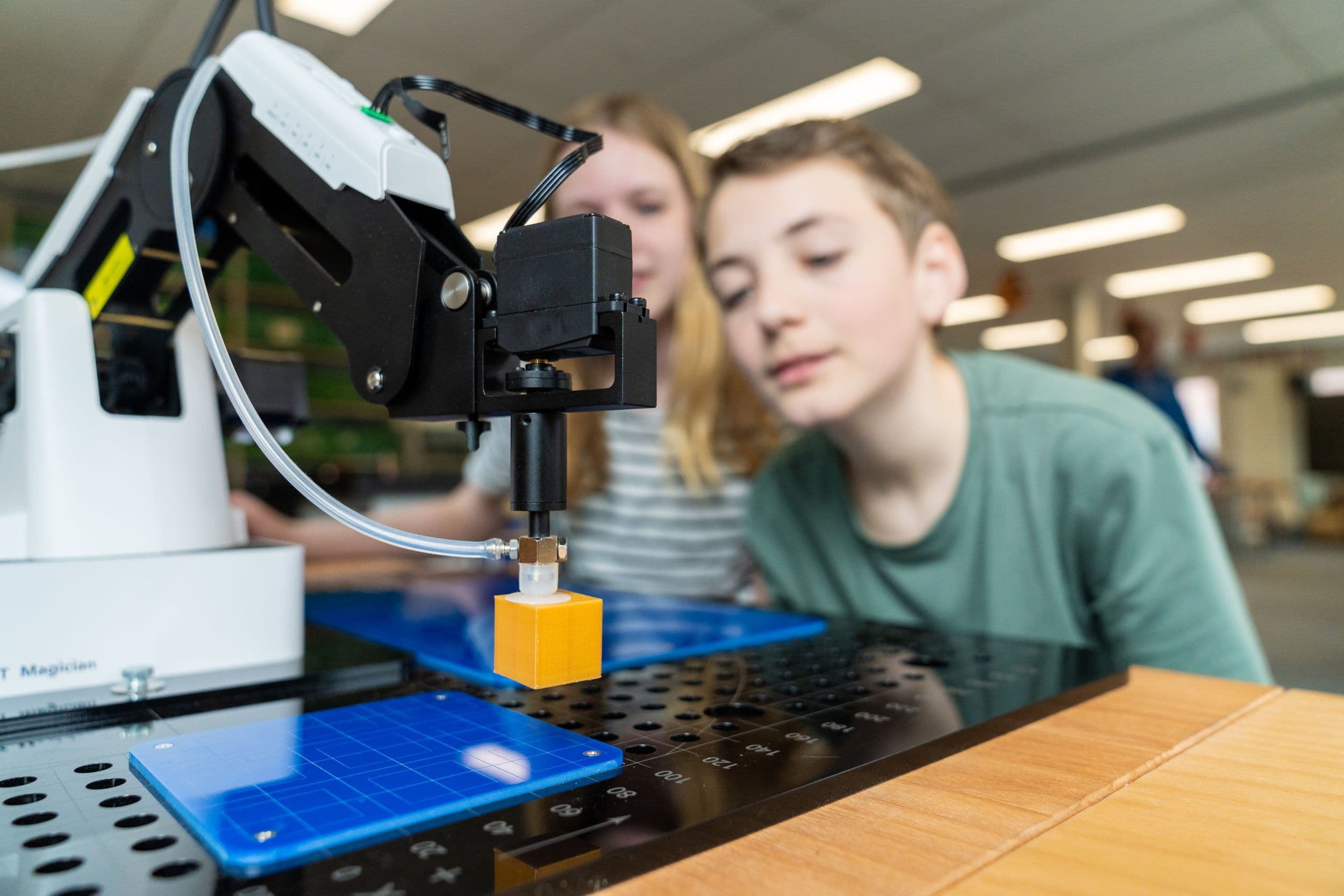 Leerlingen bedienen een Dobot Magician robotarm in het technieklokaal