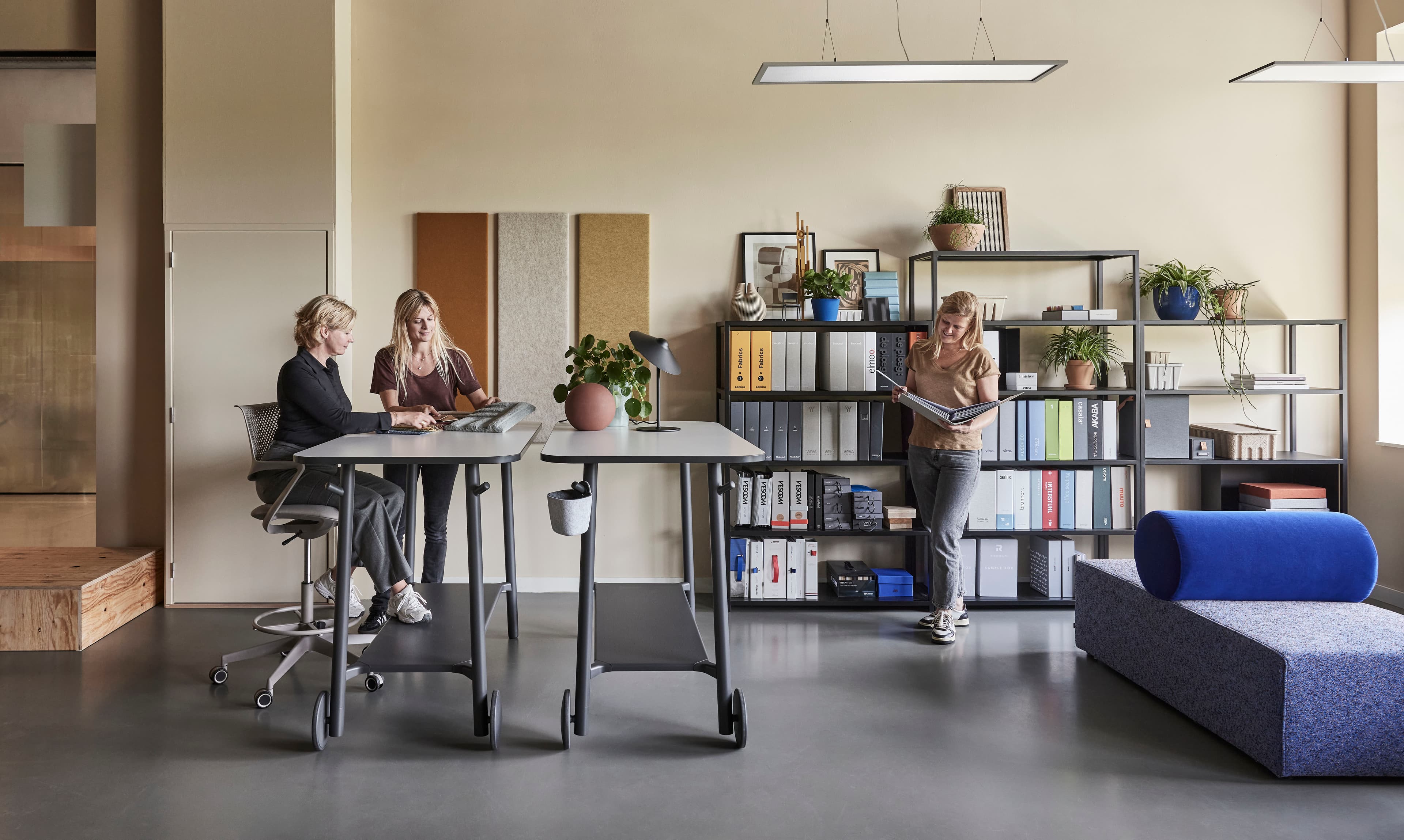 Collega’s overleggen aan een hoge tafel in een kantoor met open kasten en een loungebank