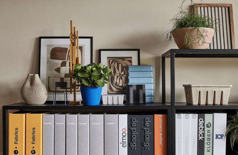 Zwarte open kast met ordners, planten, ingelijste kunst en decoratieve accessoires.